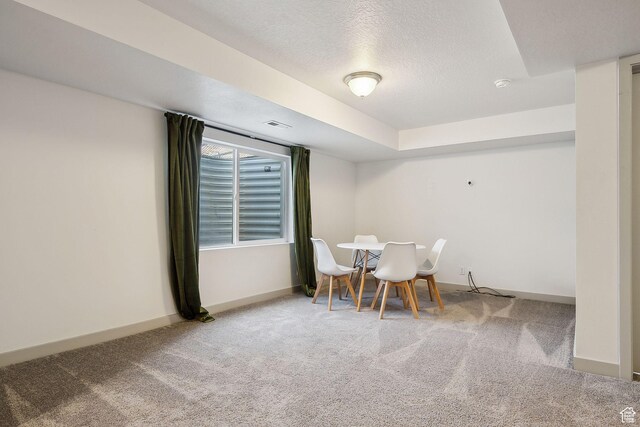 carpeted dining area with a textured ceiling, baseboards, and visible vents