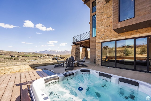 exterior space with a patio, an outdoor hot tub, and a mountain view
