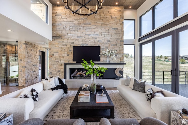 living room featuring a towering ceiling, a notable chandelier, wood finished floors, wooden ceiling, and a fireplace