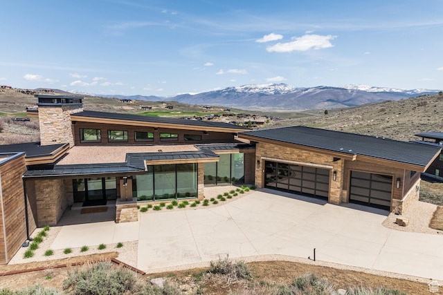 prairie-style house featuring stone siding, a standing seam roof, metal roof, and a mountain view
