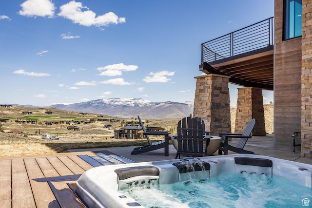 exterior space featuring a mountain view, a patio, and an outdoor hot tub