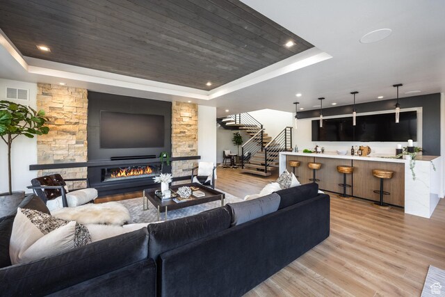 9881 N Uinta Dr, Kamas, UT 84036 - living room featuring light wood-style flooring, a tray ceiling, visible vents, stairs, and a fireplace