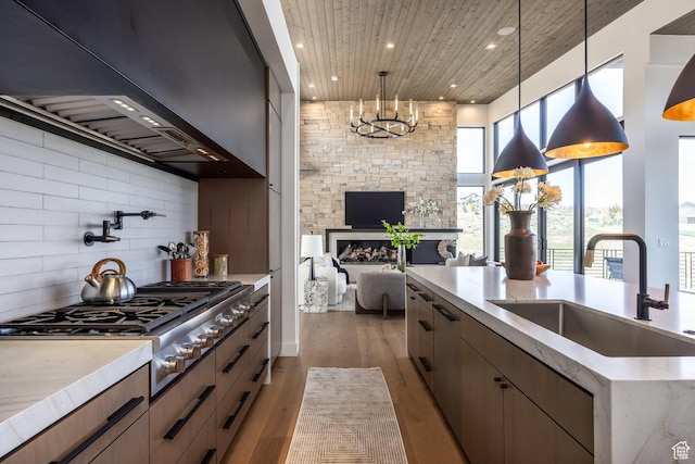 kitchen with stainless steel gas stovetop, a sink, tasteful backsplash, open floor plan, and custom range hood
