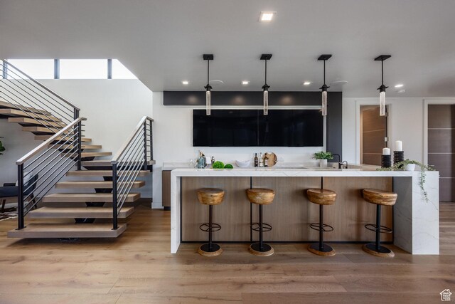 bar with light wood-style flooring, decorative light fixtures, recessed lighting, and stairway