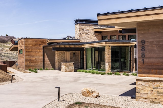 back of property featuring stone siding and a patio