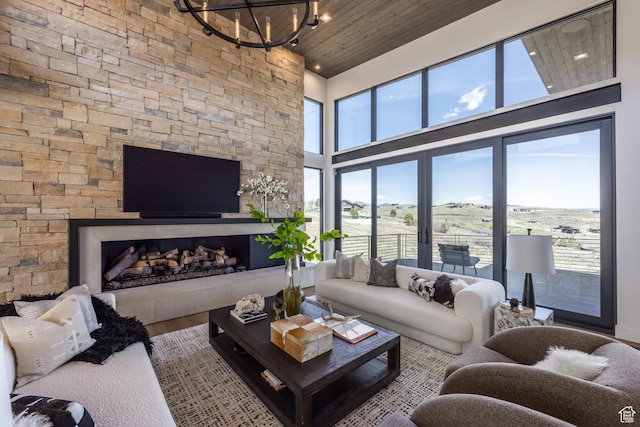 living room with a towering ceiling, an inviting chandelier, wood finished floors, wooden ceiling, and a fireplace