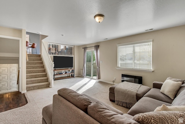 carpeted living area featuring stairway, baseboards, and visible vents