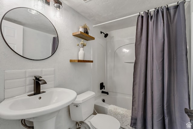 bathroom featuring a textured wall, shower / tub combo with curtain, a sink, and toilet