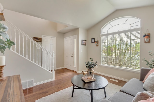 living area featuring stairway, vaulted ceiling, wood finished floors, and visible vents