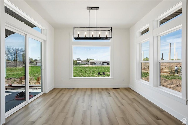 2649 N 3975 W, Plain City, UT 84404 - unfurnished dining area with light wood-style floors, a wealth of natural light, and an inviting chandelier