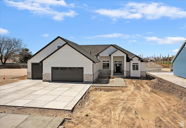 view of front of home with an attached garage, stucco siding, stone siding, and concrete driveway