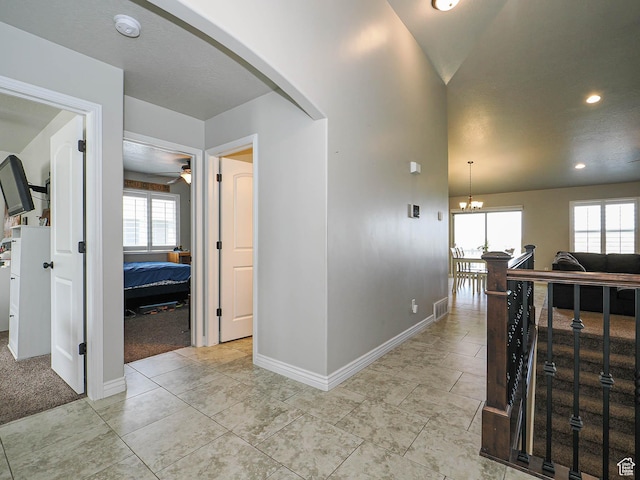 hallway featuring a chandelier, arched walkways, baseboards, visible vents, and recessed lighting