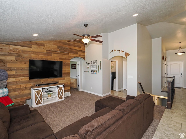 living area featuring arched walkways, vaulted ceiling, a ceiling fan, and wood walls