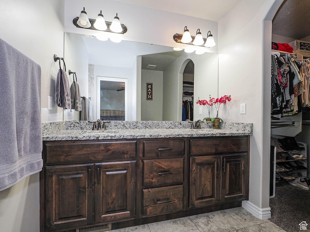 full bath featuring a walk in closet, double vanity, and a sink