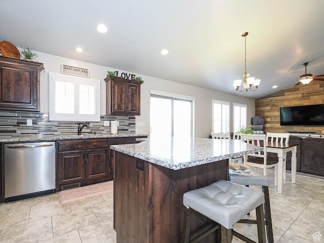 kitchen with lofted ceiling, a kitchen breakfast bar, light stone counters, stainless steel dishwasher, and open floor plan