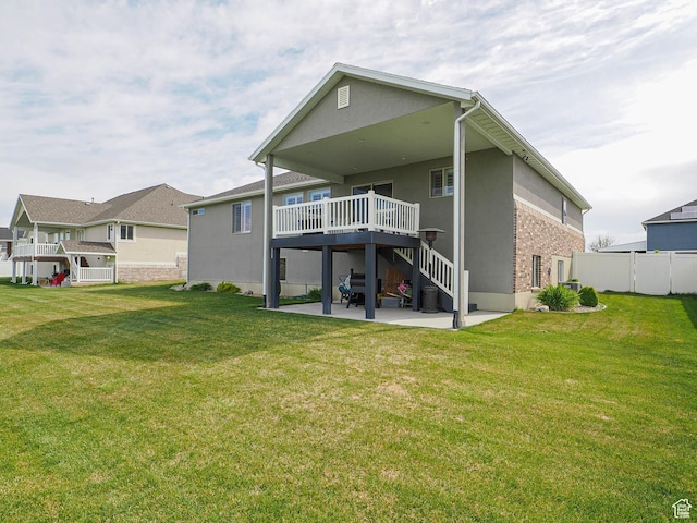 back of property with a lawn, a wooden deck, fence, and a patio