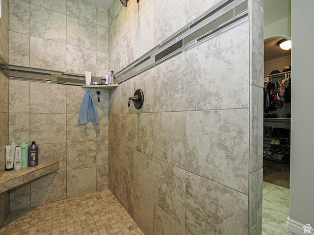 full bath with a spacious closet and a tile shower