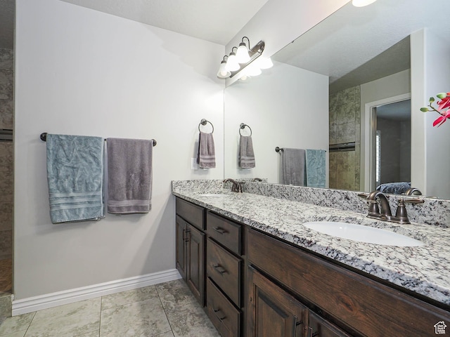 full bathroom featuring double vanity, baseboards, and a sink