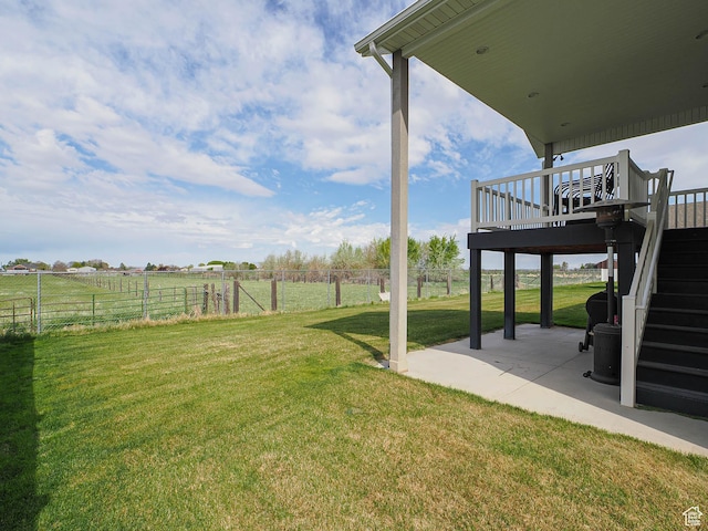 view of yard with a deck, a rural view, fence, a patio, and stairs