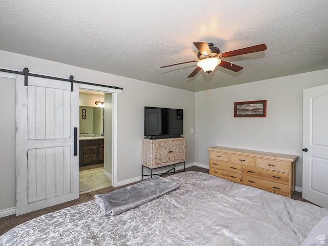 carpeted bedroom with a barn door, a textured ceiling, a ceiling fan, and baseboards