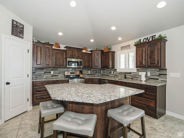 kitchen featuring a breakfast bar, a kitchen island, appliances with stainless steel finishes, and decorative backsplash