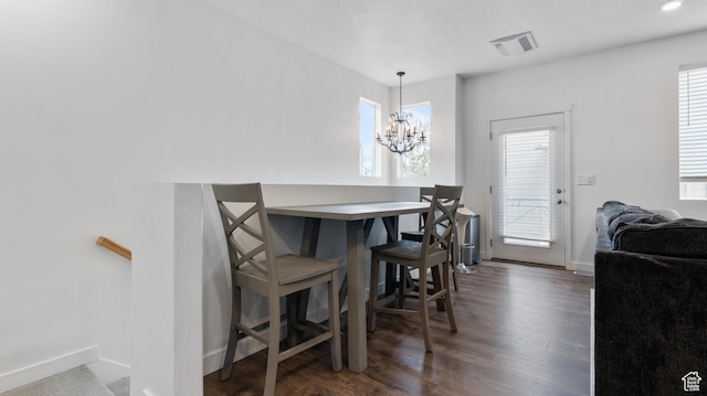 dining room featuring dark wood-type flooring, a chandelier, visible vents, and baseboards