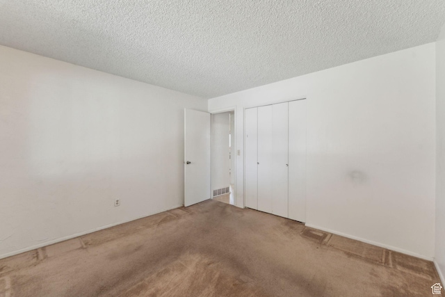 unfurnished bedroom featuring carpet flooring, a textured ceiling, visible vents, and a closet