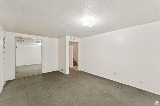 empty room featuring baseboards, carpet, and stairs