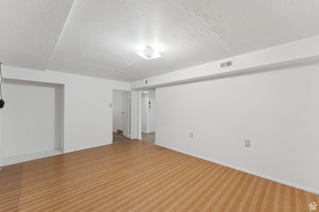 empty room featuring a textured ceiling, visible vents, and baseboards