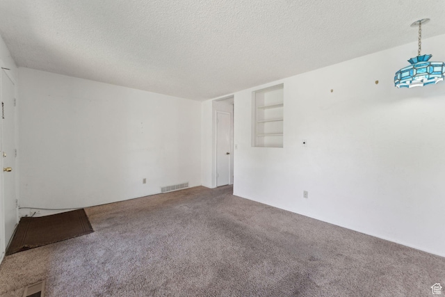 unfurnished room featuring visible vents, carpet flooring, and a textured ceiling