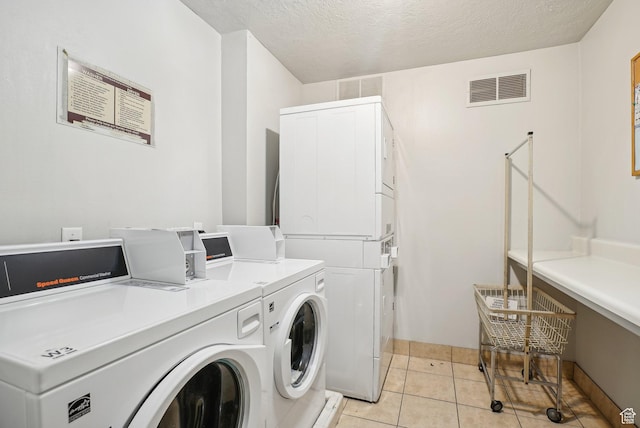 shared laundry with separate washer and dryer, a textured ceiling, light tile patterned floors, and baseboards