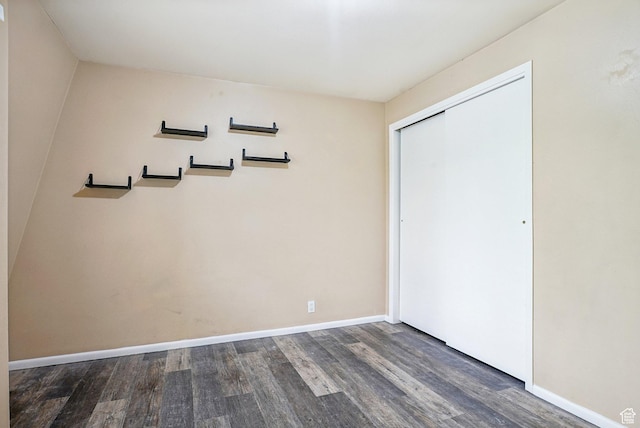 unfurnished bedroom featuring wood finished floors, a closet, and baseboards