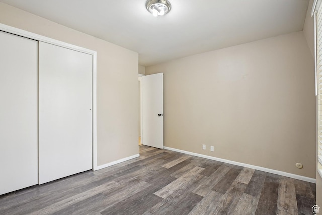 unfurnished bedroom with wood finished floors, a closet, and baseboards