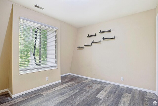 unfurnished room featuring healthy amount of natural light, wood finished floors, and baseboards