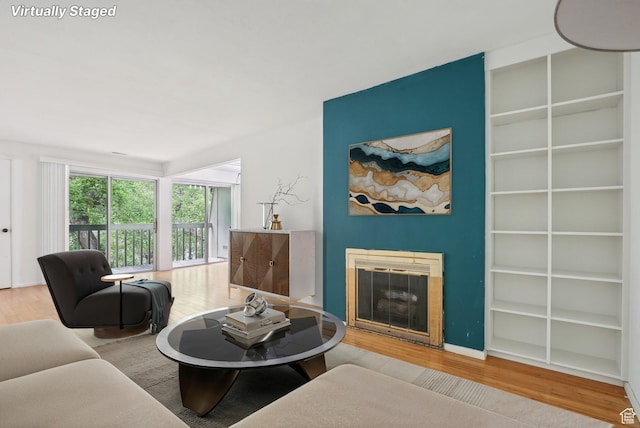 living area with wood finished floors and a glass covered fireplace