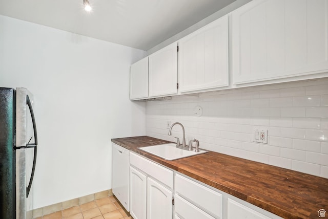 kitchen featuring freestanding refrigerator, a sink, tasteful backsplash, wooden counters, and white cabinetry
