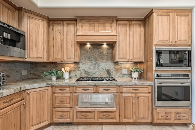 2410 W Entrada Trl Unit 15, St George, UT 84770 - kitchen with light stone counters, premium range hood, a warming drawer, tasteful backsplash, and appliances with stainless steel finishes