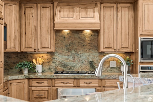 2410 W Entrada Trl Unit 15, St George, UT 84770 - kitchen with light brown cabinets, built in microwave, stainless steel gas cooktop, premium range hood, and backsplash