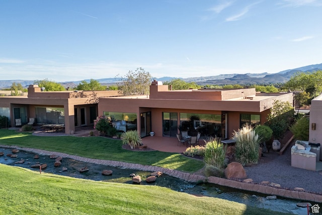 2410 W Entrada Trl Unit 15, St George, UT 84770 - back of property featuring stucco siding, a mountain view, a patio, and a lawn