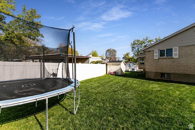view of yard with a fenced backyard, an outbuilding, a storage unit, and a trampoline