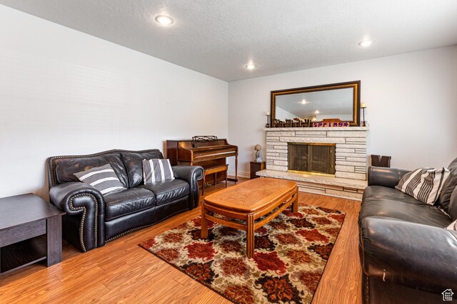 living room with light wood finished floors, a textured ceiling, a fireplace, and recessed lighting