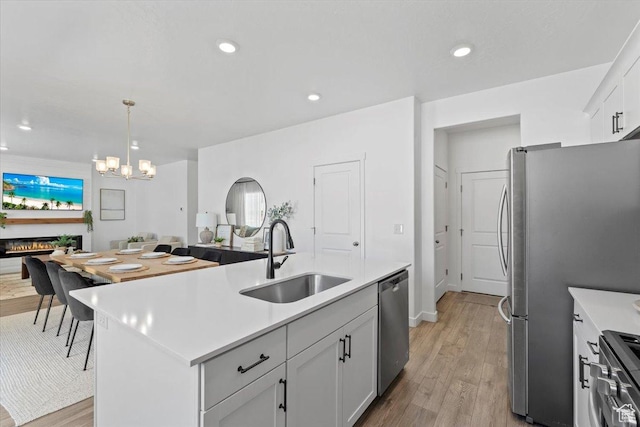 1158 E Bearing Dr S, Saratoga Springs, UT 84045 - kitchen featuring a sink, light wood-type flooring, an inviting chandelier, light countertops, and appliances with stainless steel finishes
