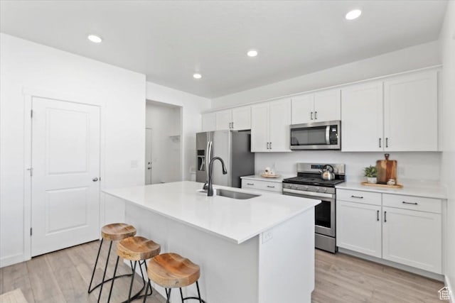 1158 E Bearing Dr S, Saratoga Springs, UT 84045 - kitchen with light wood finished floors, an island with sink, a kitchen breakfast bar, stainless steel appliances, and a sink