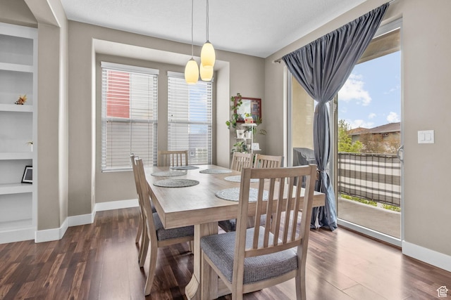 dining room featuring baseboards, wood finished floors, and built in shelves