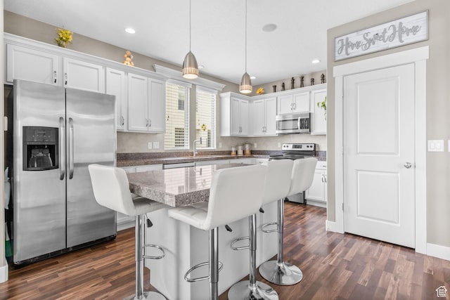 kitchen with recessed lighting, dark wood finished floors, stainless steel appliances, a breakfast bar area, and white cabinetry