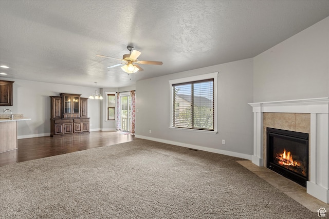 286 S Bing Cherry Way, Layton, UT 84040 - unfurnished living room featuring dark carpet, baseboards, a tiled fireplace, a textured ceiling, and ceiling fan