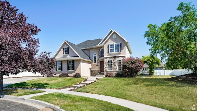 view of front of property with stone siding, a front yard, stucco siding, and fence