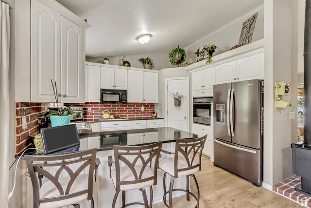 217 W 990 N, American Fork, UT 84003 - kitchen with a peninsula, dark countertops, white cabinetry, backsplash, and black appliances