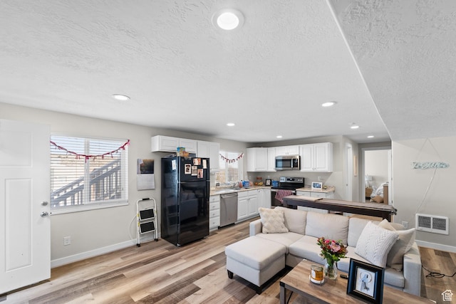 2671 E White Birch Dr, Eagle Mountain, UT 84005 - living area featuring a textured ceiling, light wood finished floors, baseboards, and visible vents