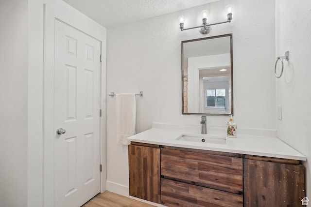 bathroom with a textured ceiling, wood finished floors, and vanity